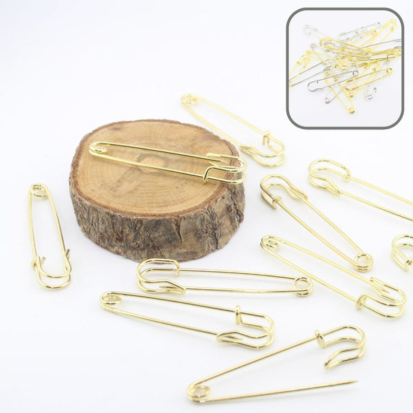 Épingles à kilt dorées pour couture, disposées sur rondin en bois, accessoires créatifs.