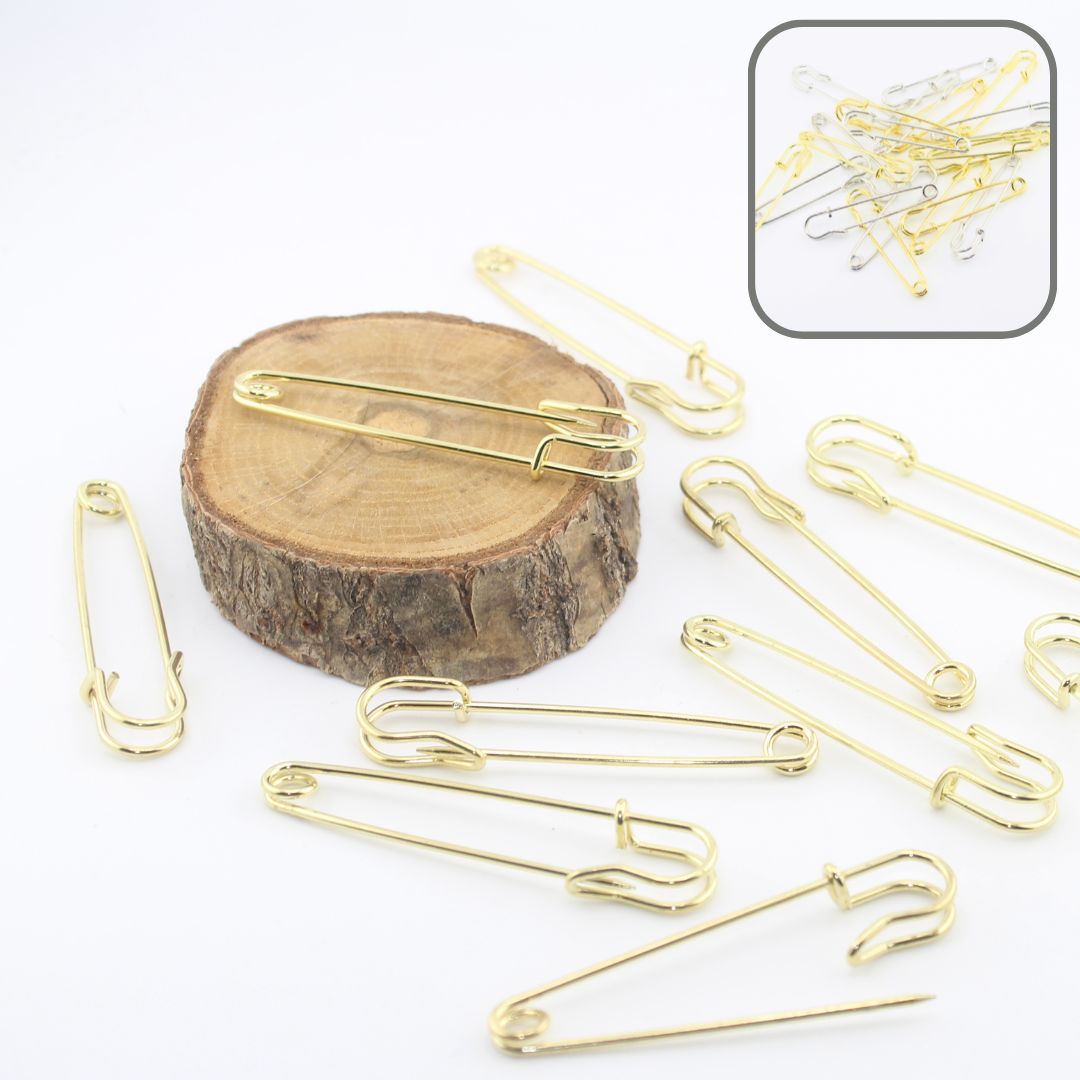 Épingles à kilt dorées pour couture, disposées sur rondin en bois, accessoires créatifs.